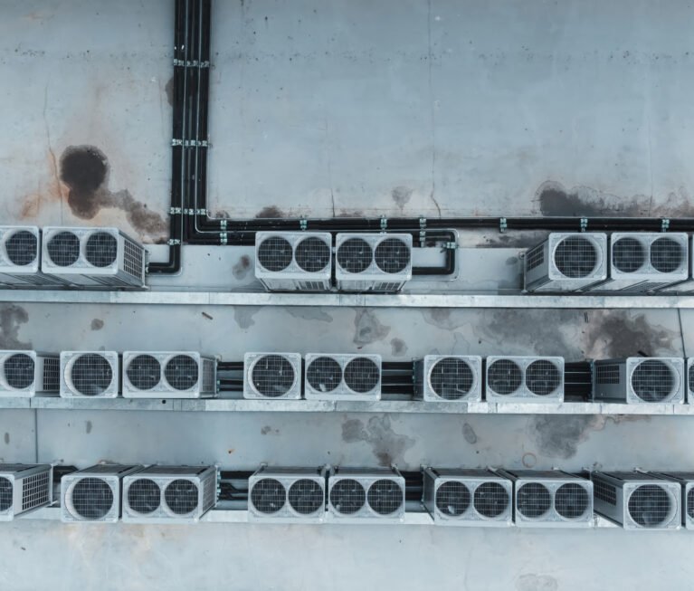Air conditioner compressor on a building's rooftop, accompanied by industrial air conditioning units and ventilation systems.