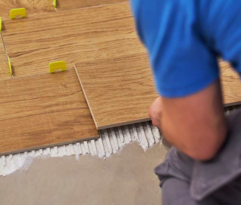 close-up of handyman placing tile spacer. Placing the floor tiles. Home improvement.