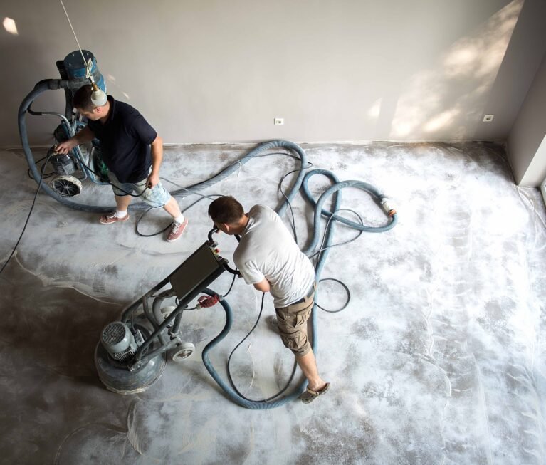 Construction worker in a family home living room that grind the concrete surface before applying epoxy flooring.Polyurethane and epoxy flooring.Concrete grinding.