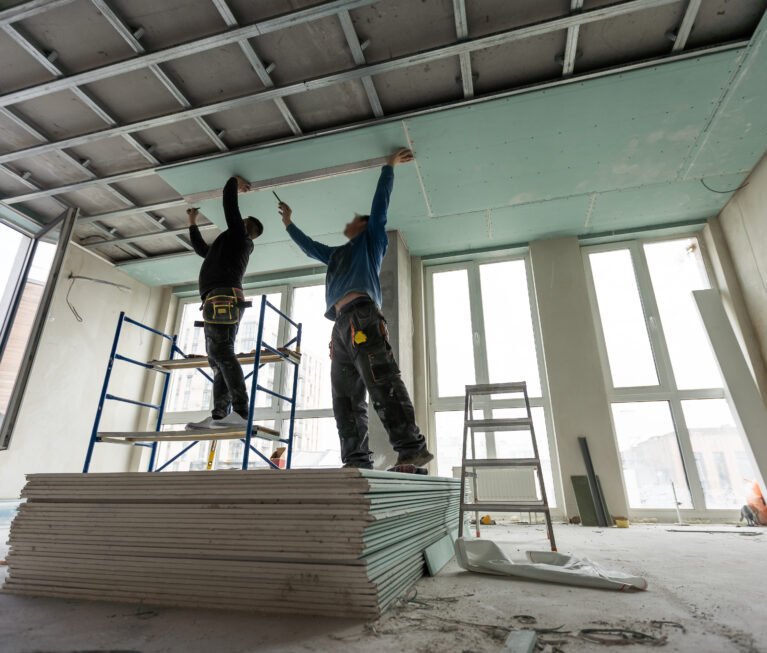 Construction worker assemble a suspended ceiling with drywall and fixing the drywall to the ceiling metal frame with screwdriver. Renovation, construction and do it yourself. High quality photo
