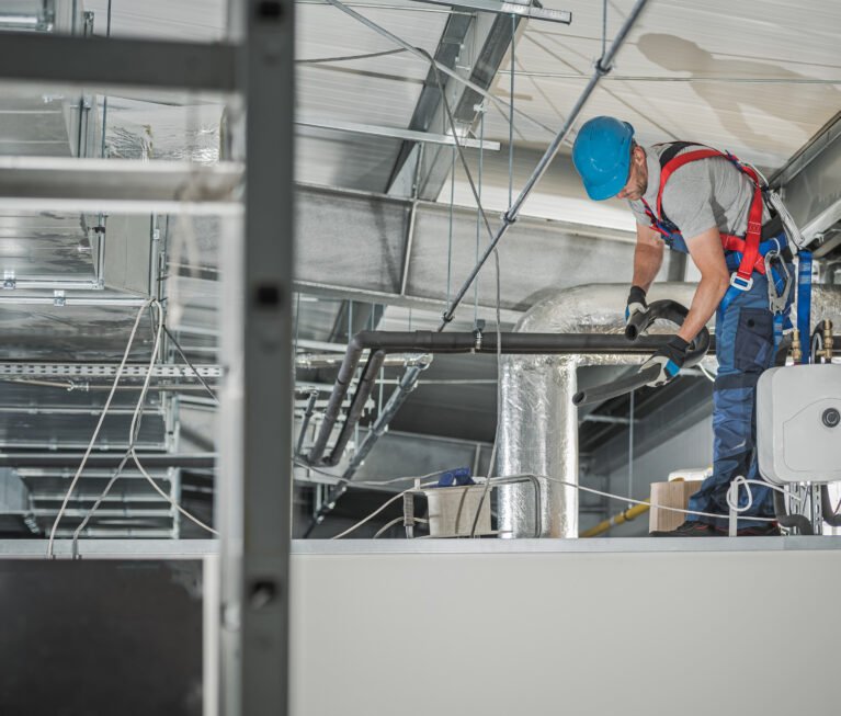 Caucasian HVAC Technician in His 40s Finishing System Assembly Inside Commercial Building Warehouse. Hot and Cold Water Line and Air Circulation Systems.