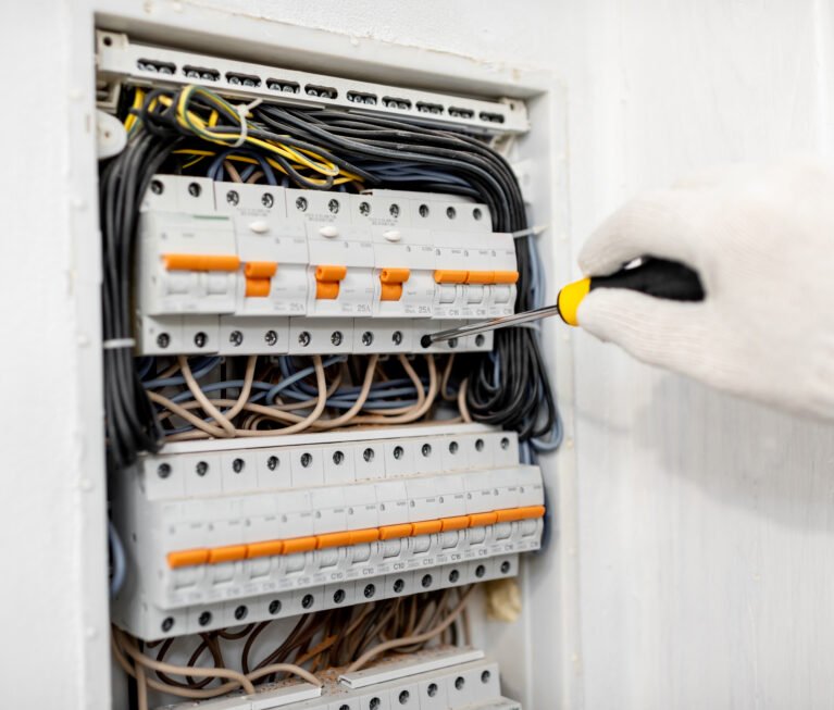 Electrician installing or repairing apartment electrical panel, close-up view