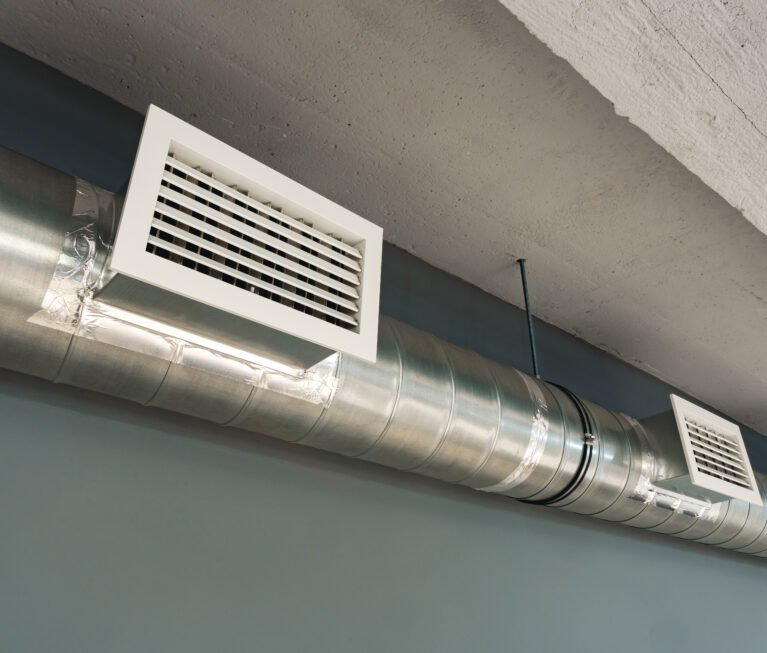 Silver ventilation pipes hanging from the ceiling inside the building close up