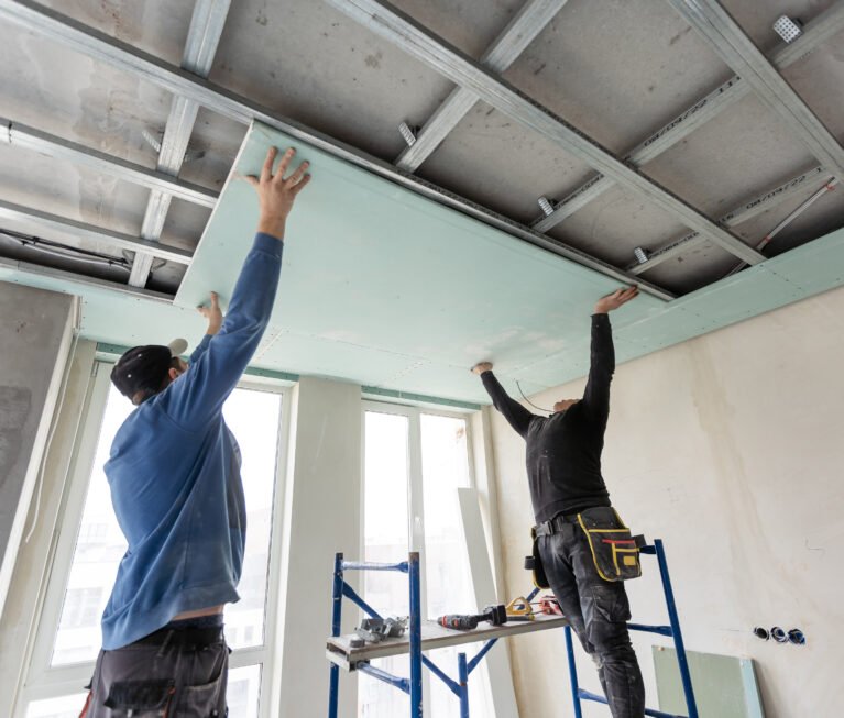 Workers fitting panel into frame of ceiling. High quality photo